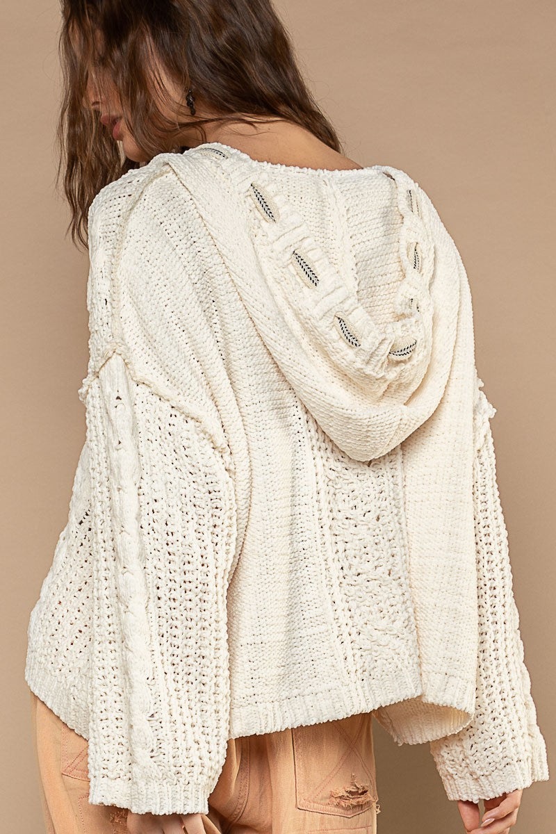 Cream medium-gauge knit sweater that shapes a v-neckline and long sleeves with drop shoulders. The boxy, roomy bodice falls to a slightly cropped hem and is topped with a hoodie. 